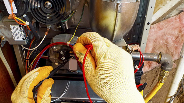 Technician testing voltage of furnace