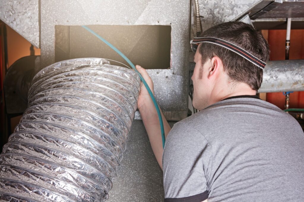 HVAC technician inspecting ductwork during cleaning process