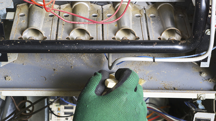 Gloved hand adjusts knob on furnace