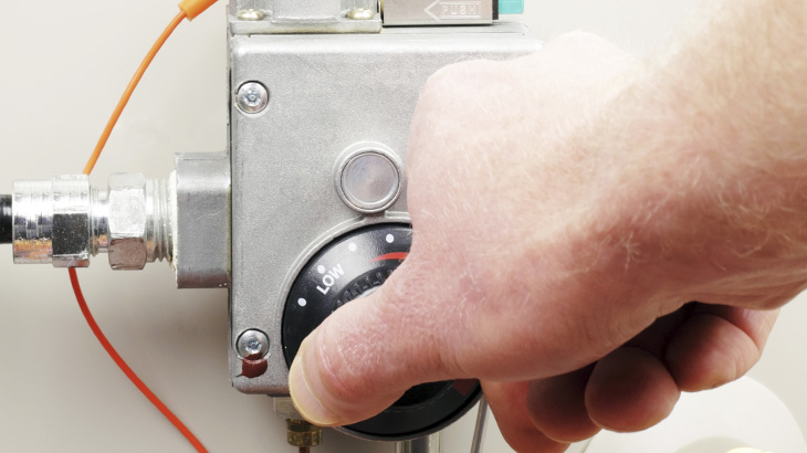 Hand tunes knob on hot water heater