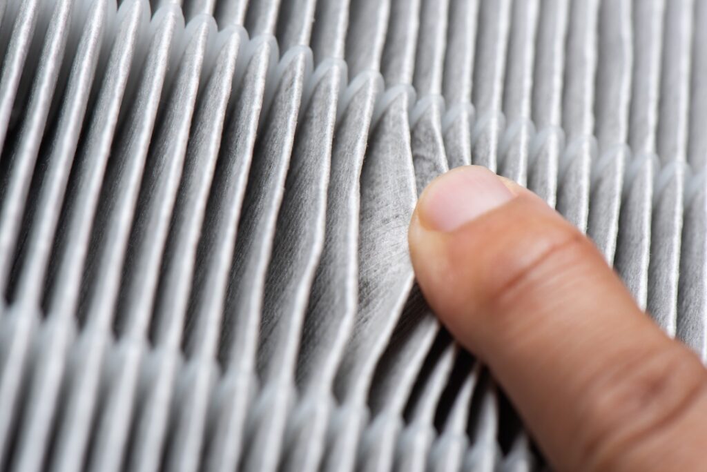 Hand touching high-quality HEPA filter for use in home HVAC system to improve air quality