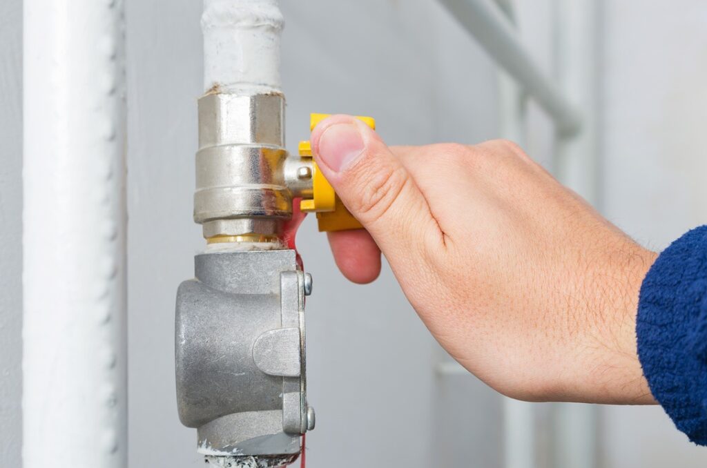 HVAC technician adjusting gas valve in home to prevent carbon monoxide leak from furnace
