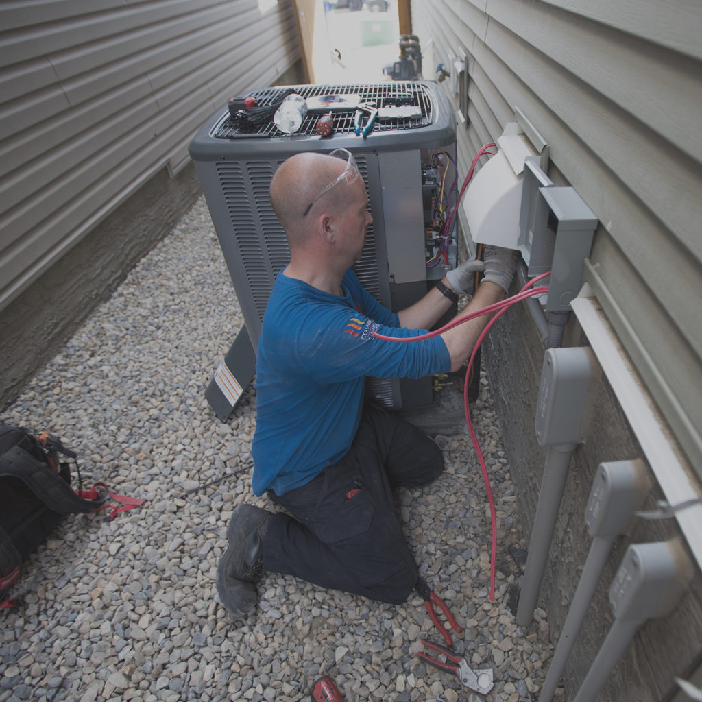 Technician installing ac unit outside home.