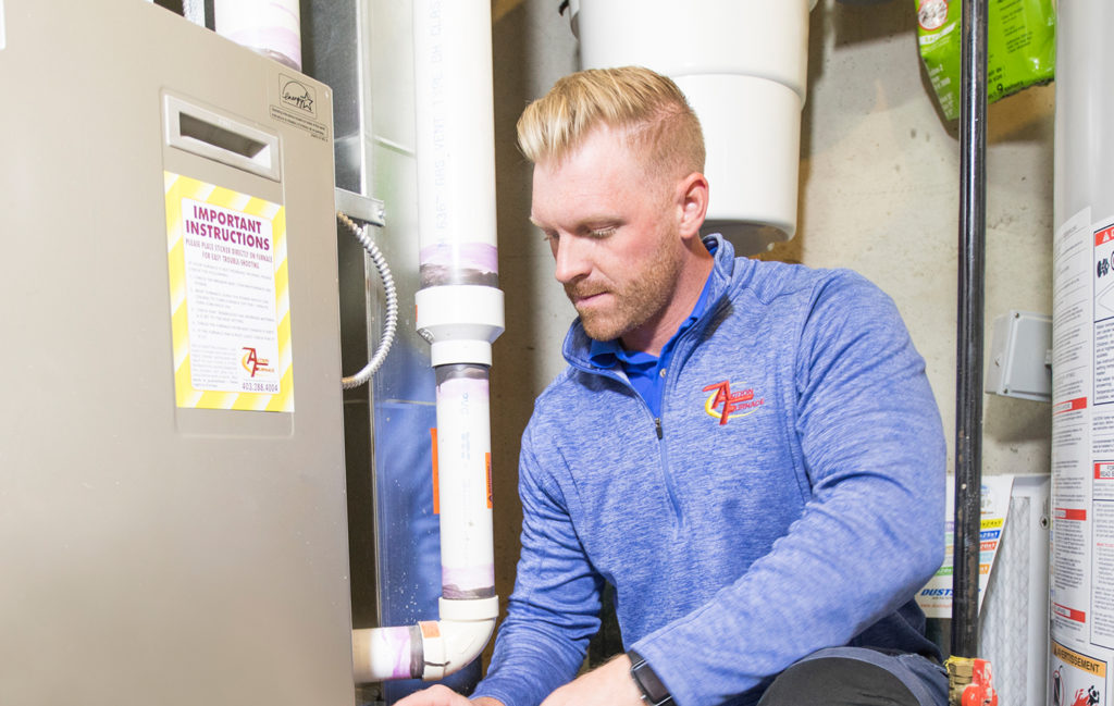 Technician inspecting gas furnace inside home.