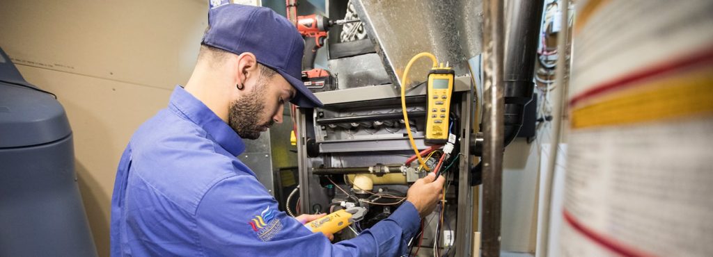 Action Furnace technician checking voltage of furnace