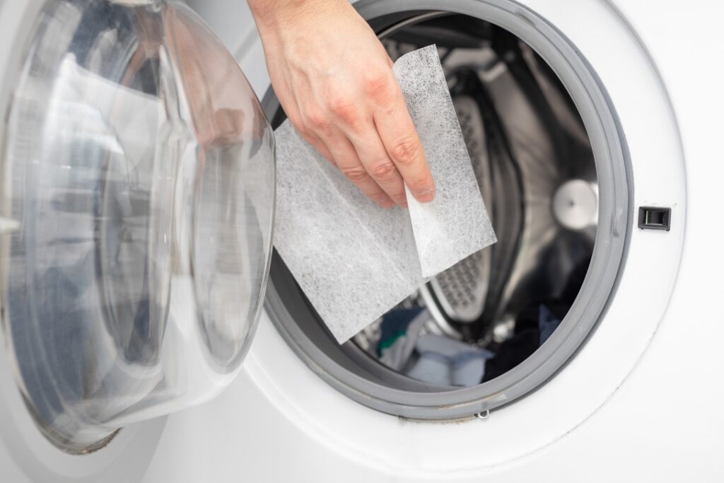 Homeowner taking dryer sheet out of laundry machine to rub on furniture and eliminate static