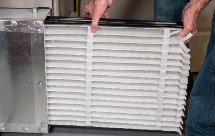 A man replacing furnace filters with a brand new, clean one