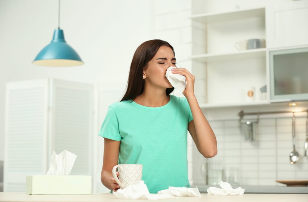 Young woman experiencing pollution in her home and using tissues to wipe nose