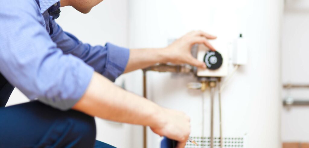 Tech adjusts temperature gauge on water heater.