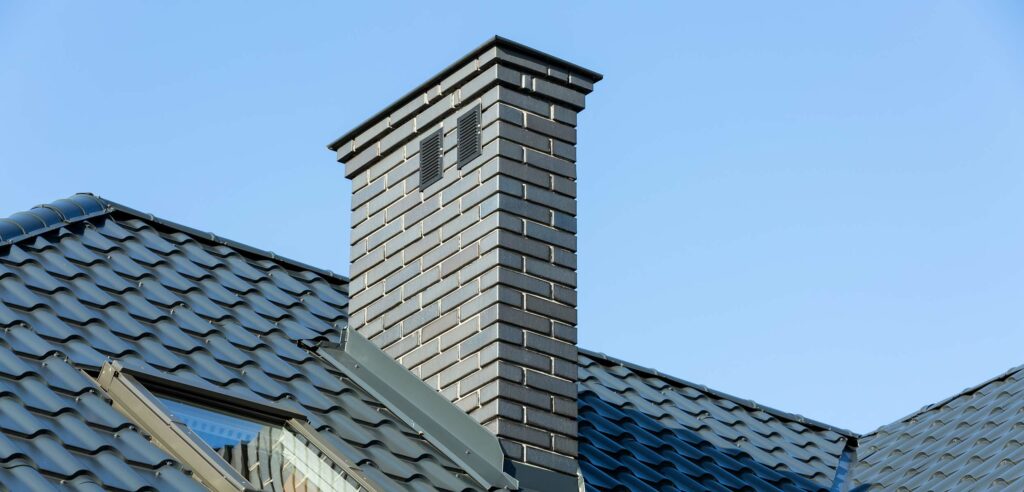 A brick chimney on sloped roof of home.