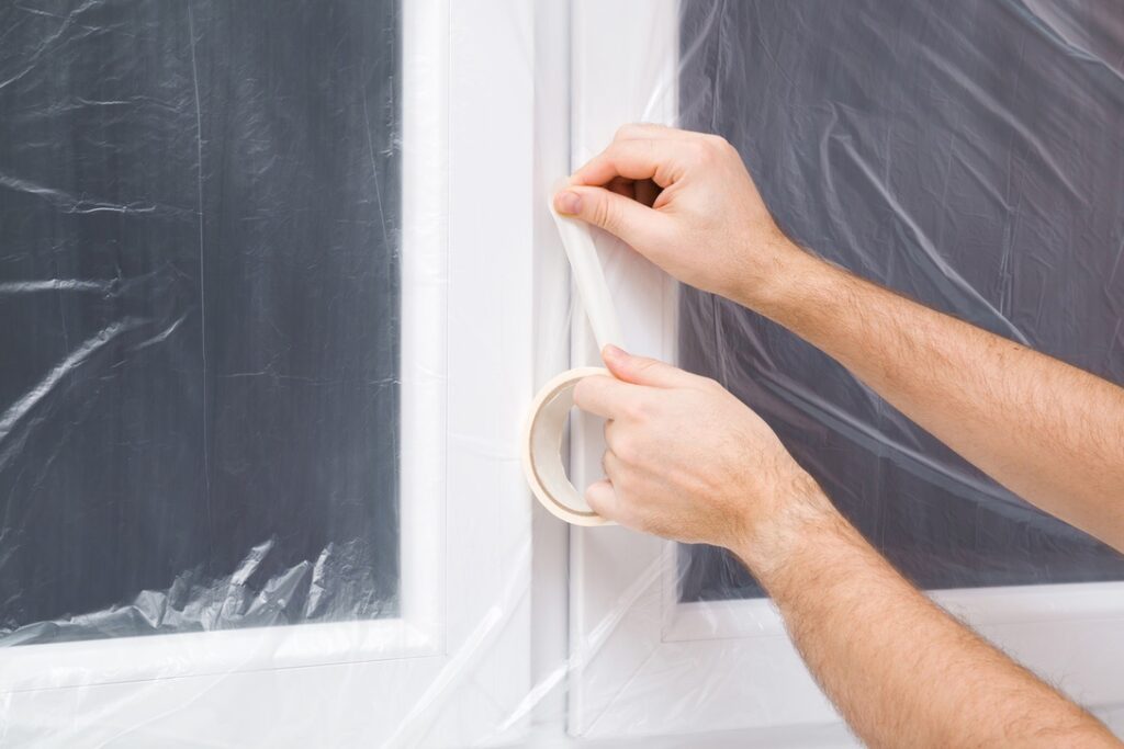 Homeowner using plastic to add extra insulation to windows