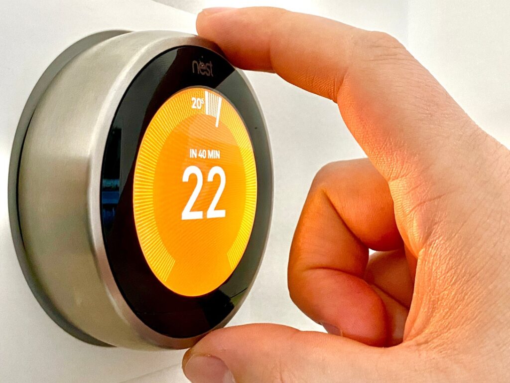 Person using programmable smart thermostat to optimize settings and improve winter heating at home