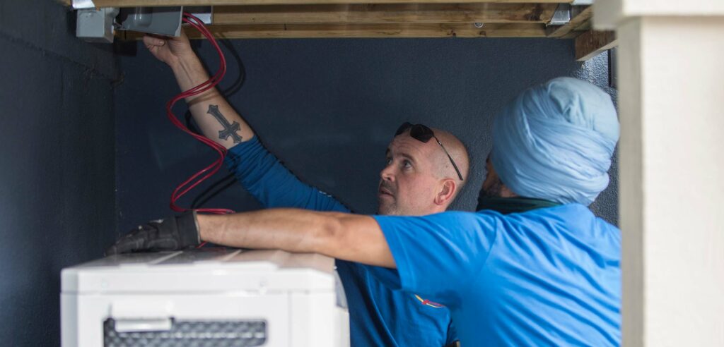 Two workers inspecting AC unit