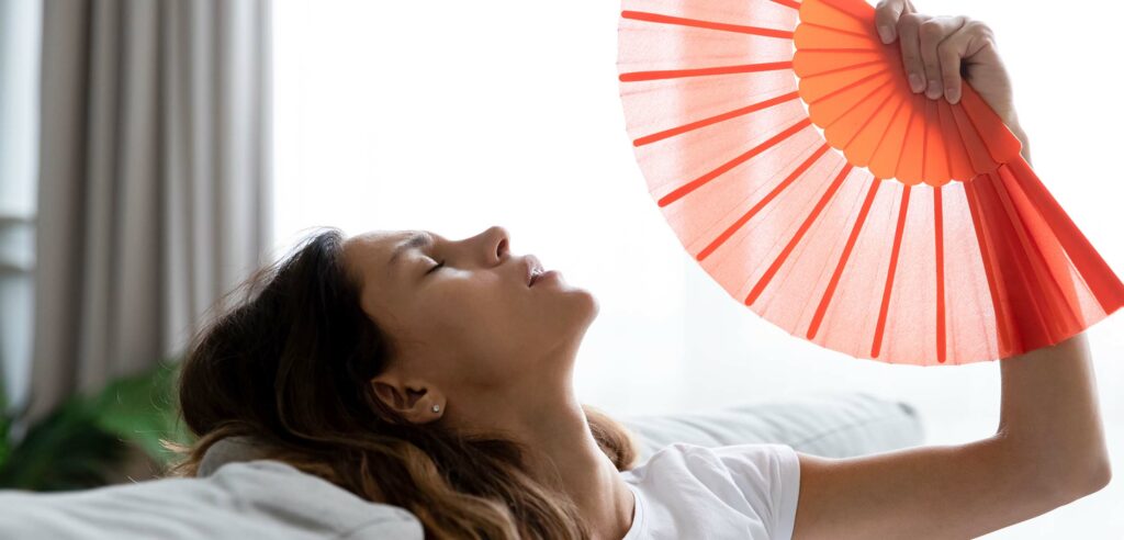 Woman using hand fan to cool herself