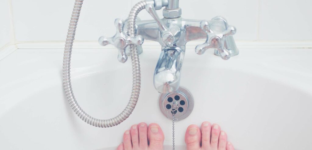 Feet in tub with stainless faucet