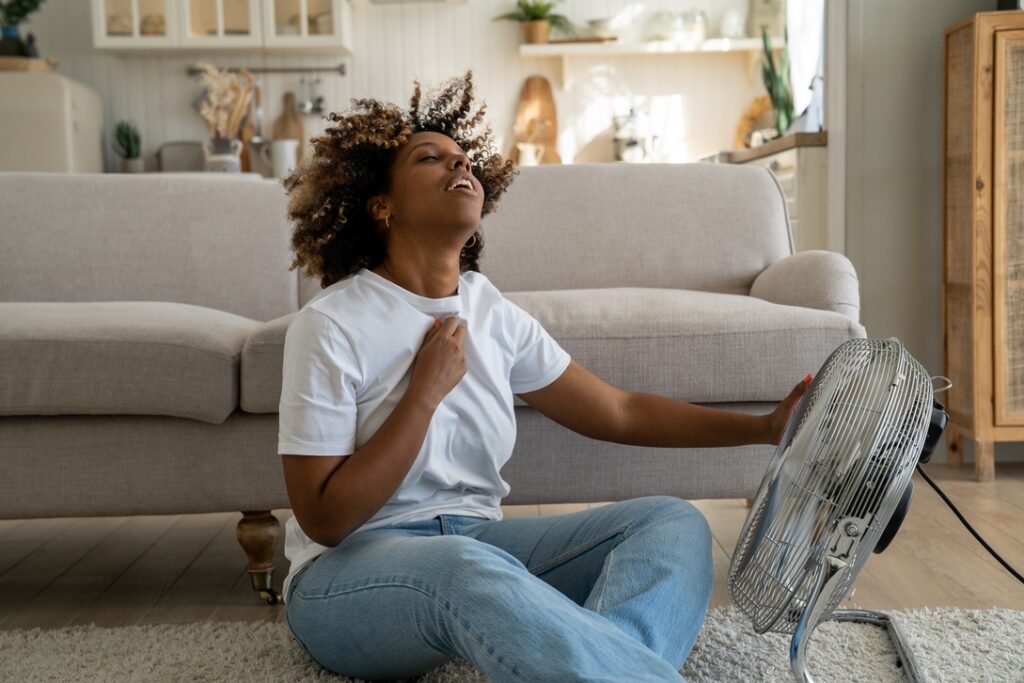 Woman sitting in front of fan in Alberta home to relax during hot summer