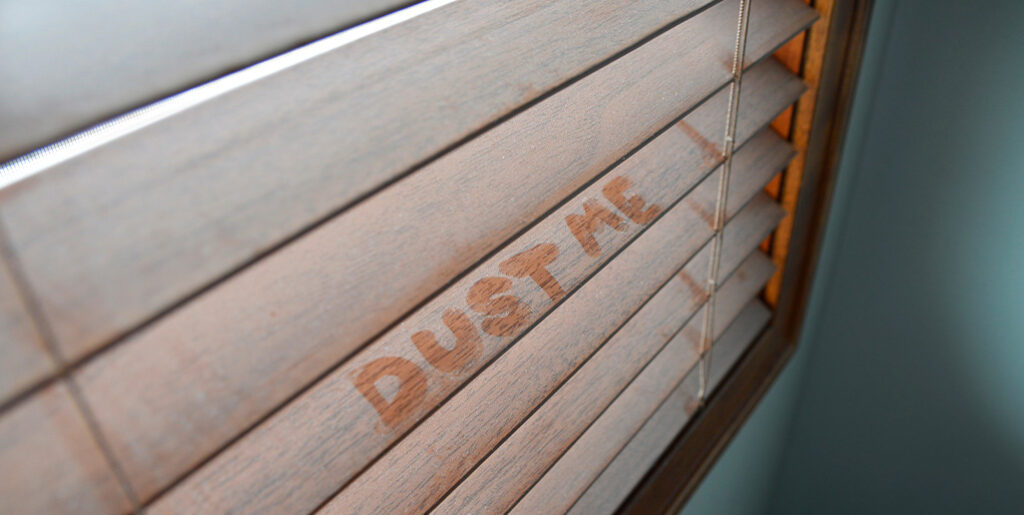 "DUST ME" drawn onto dusty blinds.