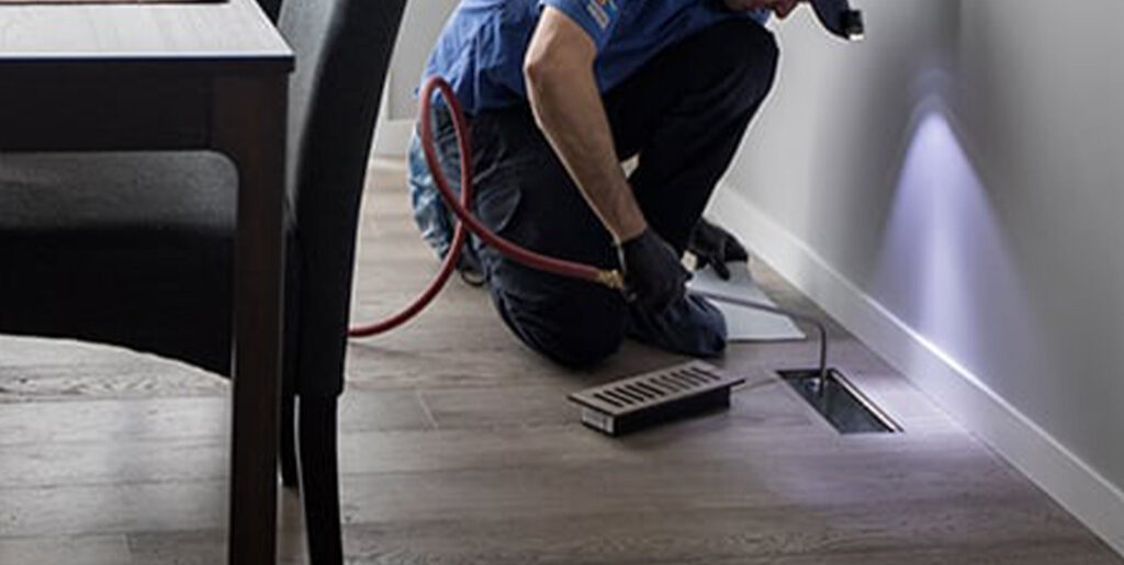 Worker vacuuming vent in home