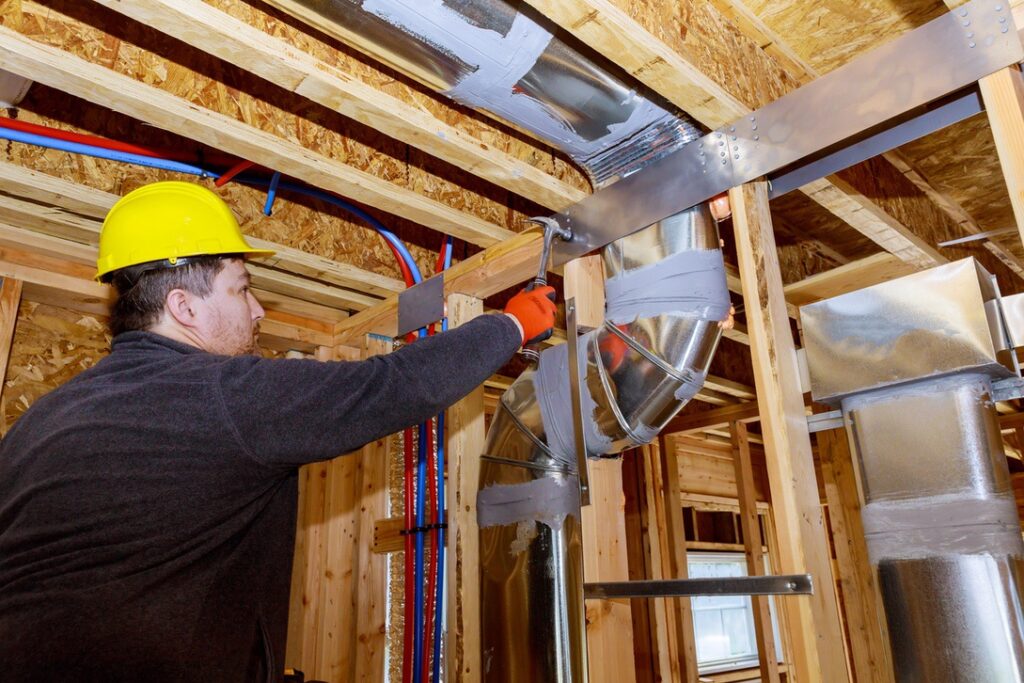 Man working on ducts in home before applying insulation