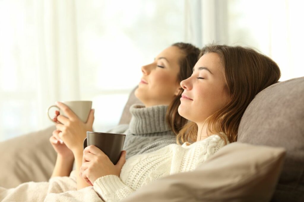 Two women laying on couch relaxing with eyes closed