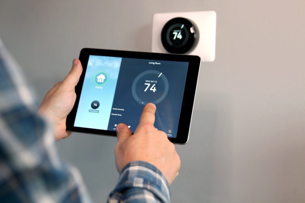 Man is Adjusting a  temperature using a tablet with smart home app in modern living room