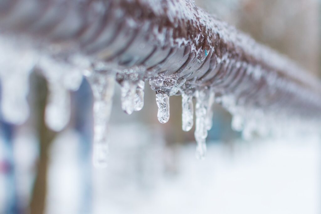 Uninsulated pipe outside home covered in ice during winter