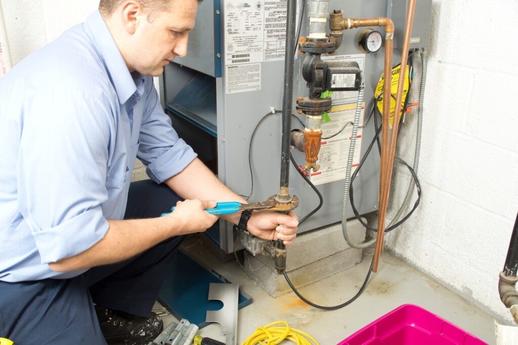 Technician servicing furnace to repair or replace damaged components causing burning smell