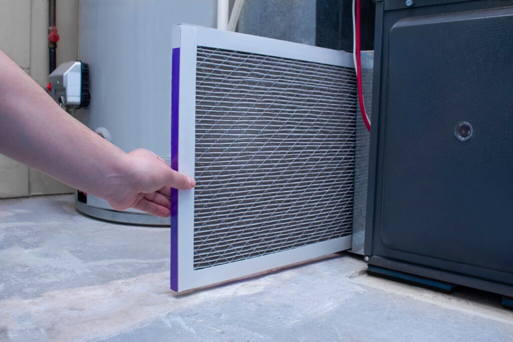 Homeowner replacing filter on new high-efficiency furnace in Alberta home