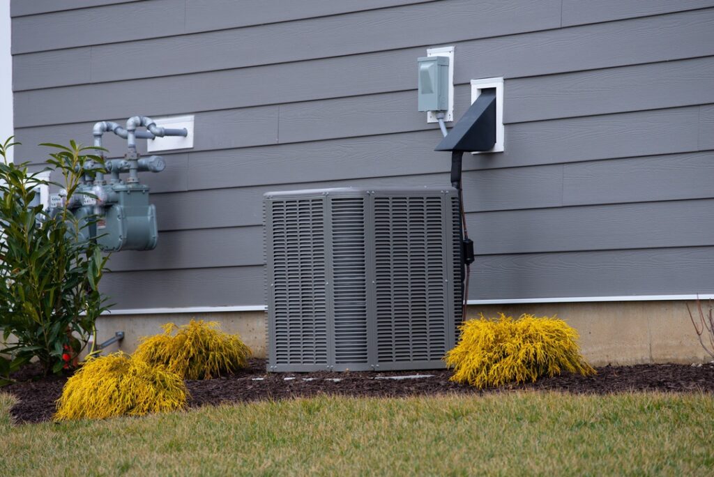 Air conditioner outdoor unit near house in summer