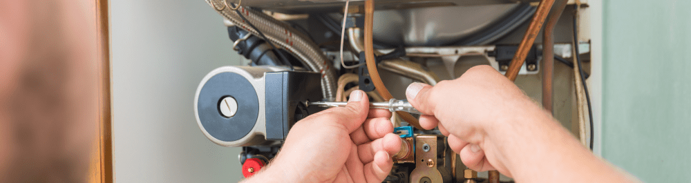 An Action Furnace technician uses a screwdriver to tighten a loose furnace component as part of a tune-up appointment. 