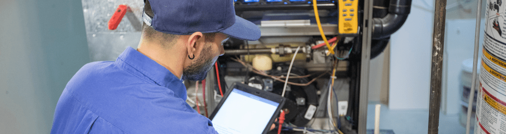 An Action Furnace technician holds a tablet and runs a diagnostic on the internal components of a furnace. This picture illustrates the thorough repair steps our technicians go through to get your furnace back up and running.