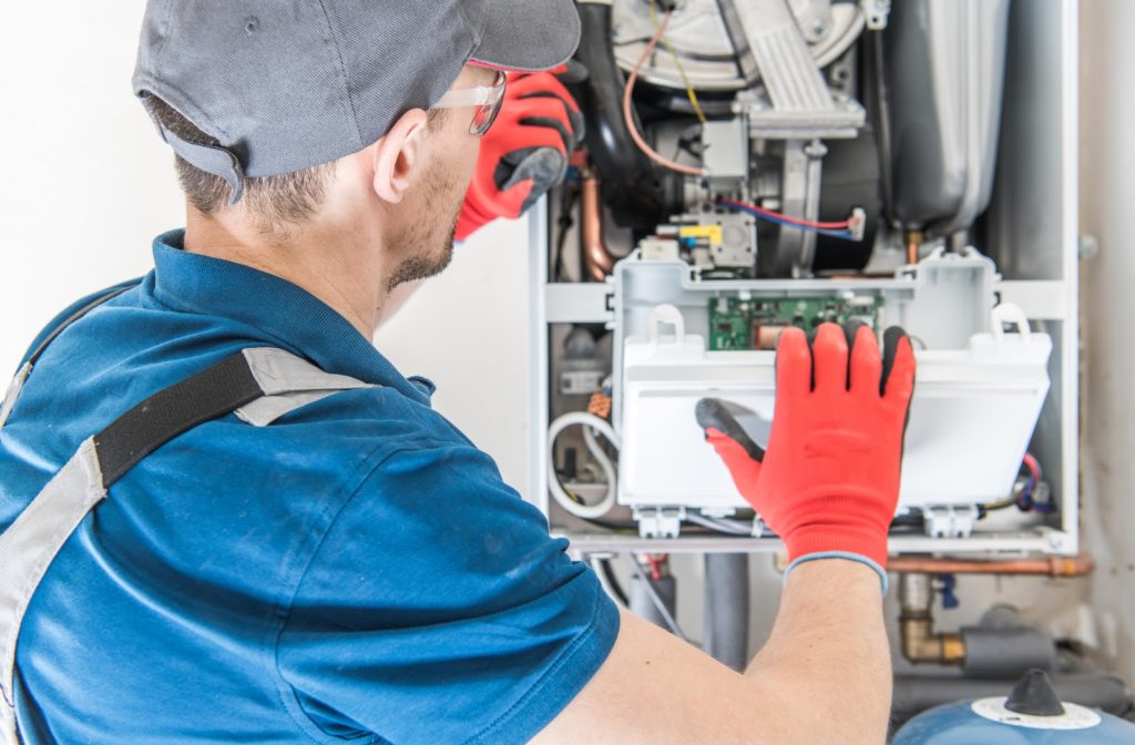 Preparing Your Central Air Conditioner For Winter Worker with orange gloves assembles A/C unit