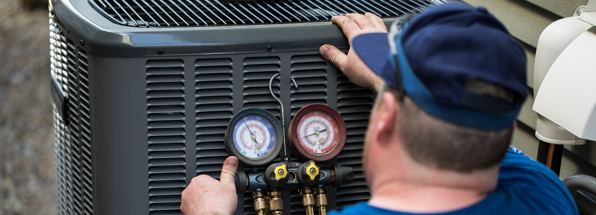 Preparing Your Central Air Conditioner For Winter Repairman adjusts dials on A/C unit