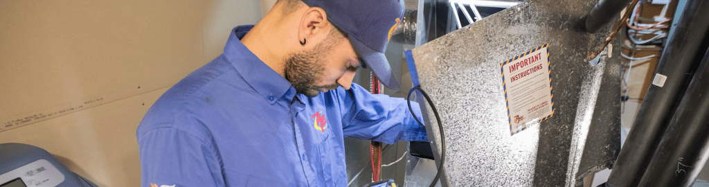An Action Furnace technician carefully inspects the interior components of a residential furnace during his tune-up process. Furnace tune-ups are crucial for performance and to get the most out of your smart thermostat.