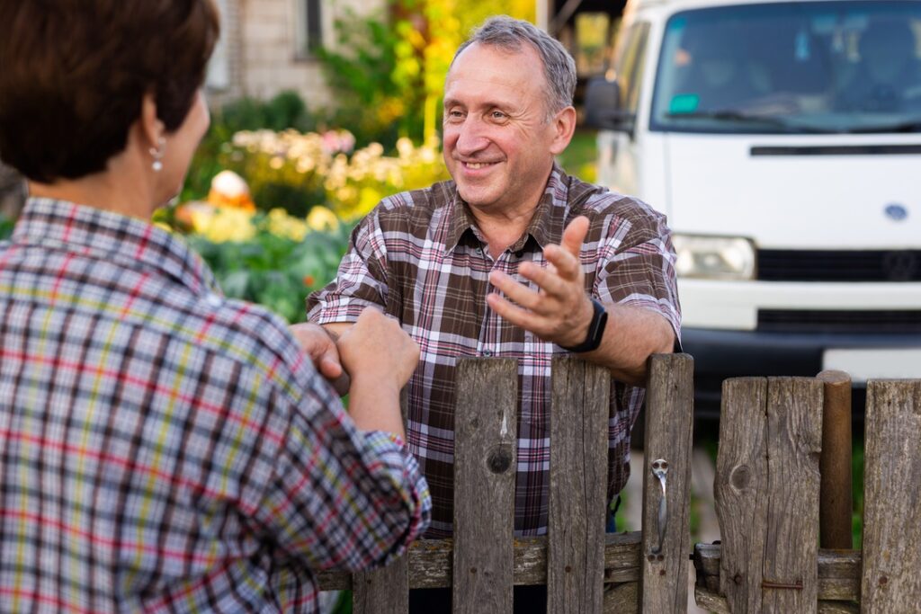 neighbors middle aged man and woman chatting near the fence in the village