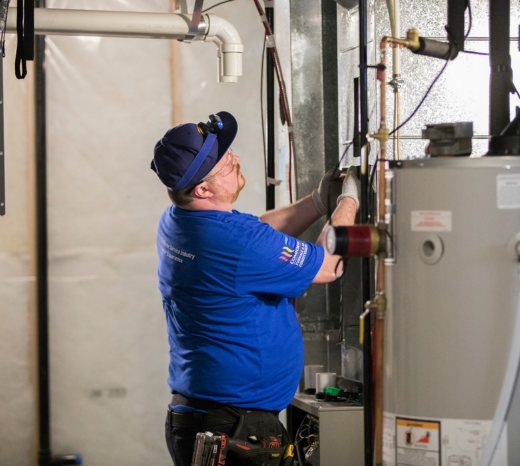 An Action Furnace technician examines a furnace to determine what repairs are needed. This image introduces a blog about steps homeowners can take if their furnace breaks down in the middle of winter.