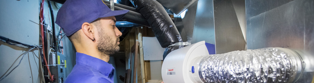 An Action Furnace technician inspects a furnace and it's connecting duct work.
