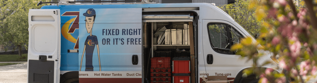 An image of an Action Furnace branded van behind a blooming plant on a warm spring day.