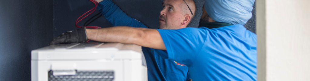 Two Action Furnace repair technicians carefully disconnect the heat pump from power so they can inspect and repair affected components
