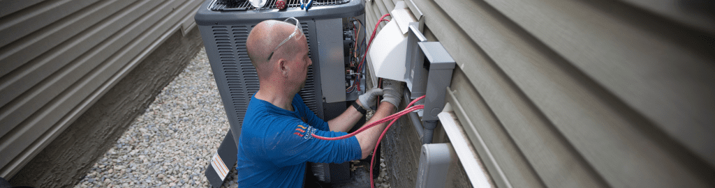 An Action Furnace technician carefully inspects an air conditioner's air flow.