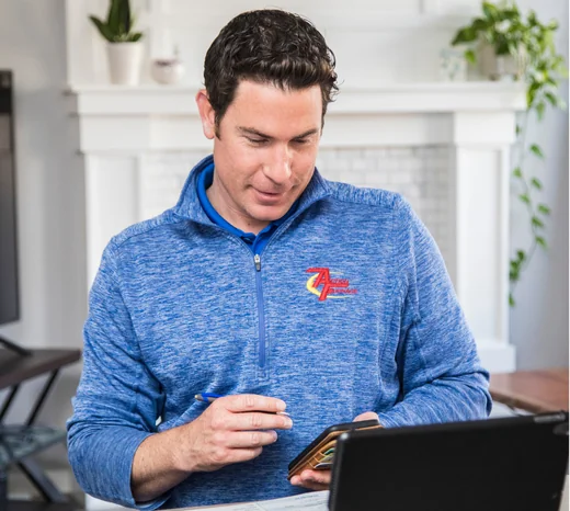 An AF technician looks at his phone and tablet while visiting a home.